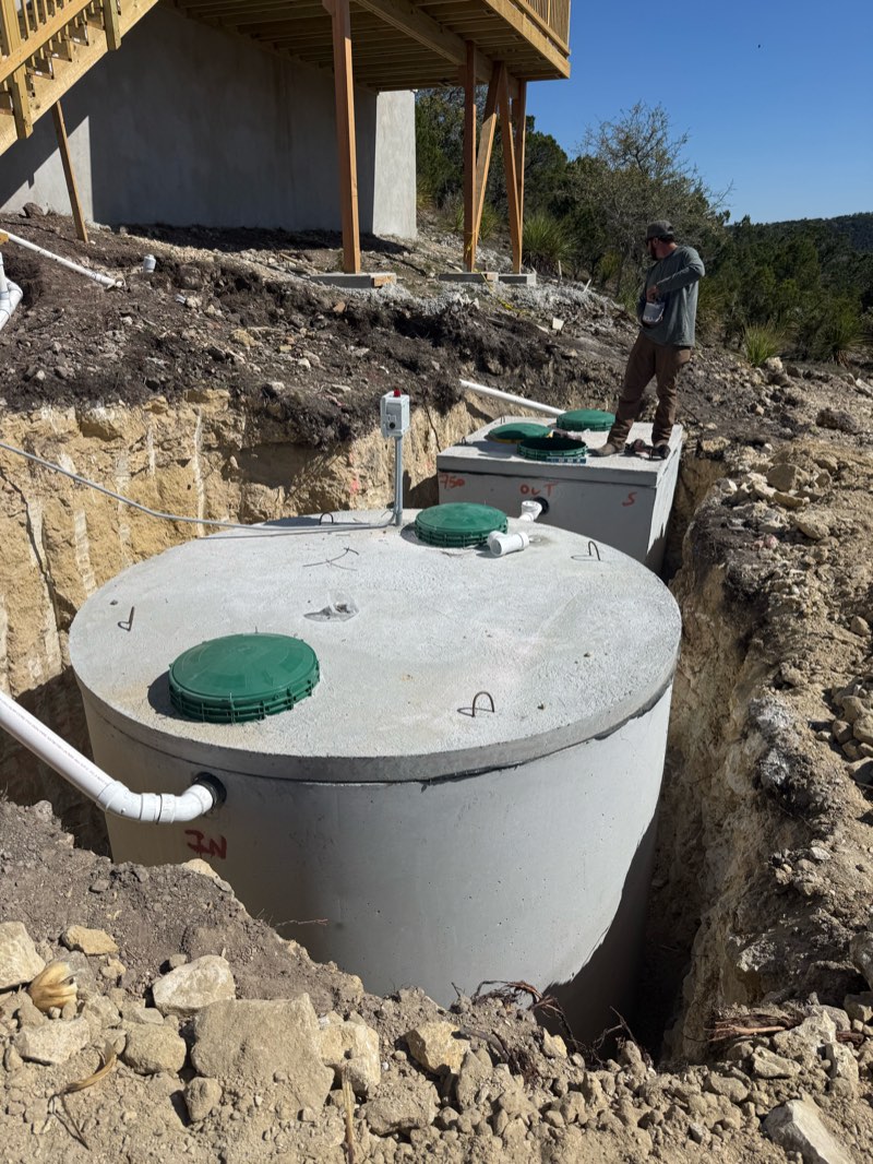 Round concrete pump tank installed below a hillside home