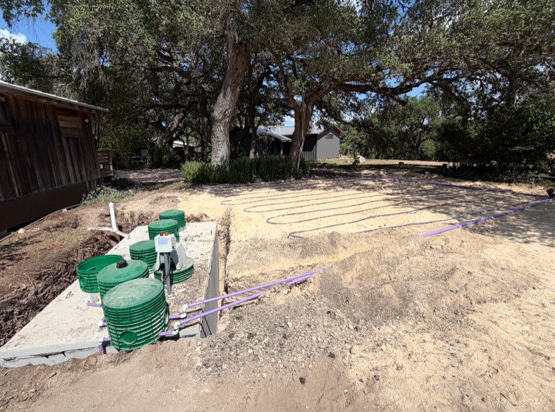 Septic tanks and field under oak trees beside a barn